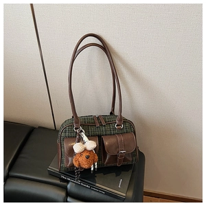 Détail du sac oreiller vintage à carreaux avec poches en cuir et breloque ours