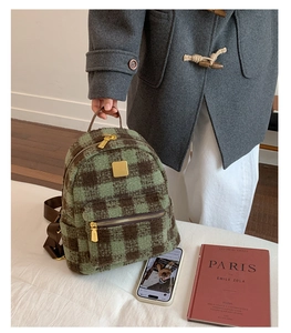 Detail of green and brown plaid plush backpack with gold metal zippers and handle
