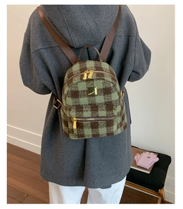 Detail view of the green and brown plaid wool backpack with golden metal square plate