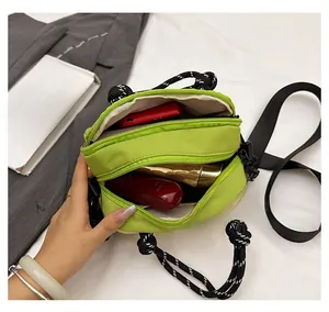 Detail of dual zipper compartments in green nylon crossbody bag showing large capacity