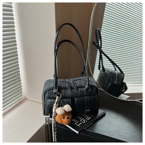 Détail du sac oreiller à carreaux avec poches latérales et breloque ours en peluche