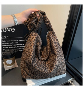 Detail of leopard print tote bag featuring a decorative knotted bow handle and zipper