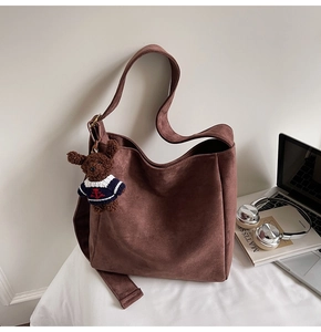 Détail du sac cabas en suédine marron foncé avec un porte-clé ours et une large bandoulière