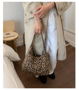 Détail du sac cabas en peluche léopard avec anses marron foncé dans un décor chaleureux