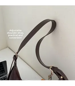 Detail of adjustable leather strap with gold buckle and chain on brown hobo bag