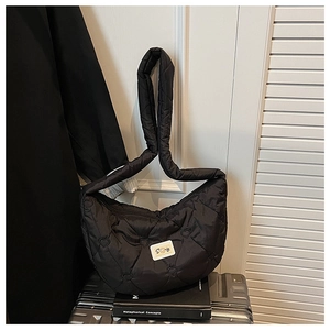 Détail du sac matelassé noir avec coutures en cœur et écusson de logo blanc