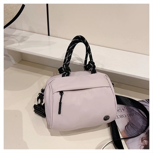 Detail of light pink nylon handbag featuring woven handles and wide shoulder strap