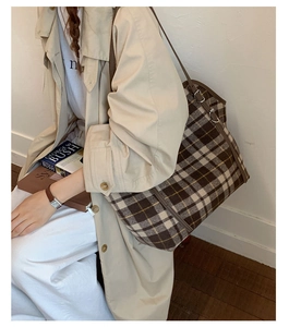 Detail of large vintage checkered tote bag with brown straps worn on the shoulder