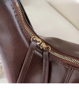 Close-up of smooth gold zipper and texture on dark brown leather crossbody bag