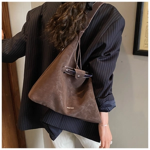 Detail of a large dark brown suede tote bag worn with a black pinstripe blazer