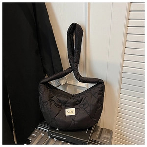 Détail du sac matelassé noir avec coutures cœurs et patch logo sur une valise