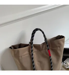 Detail of waterproof nylon tote with black and white woven rope handles and red tag