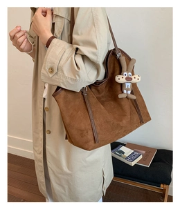 Detail of vintage brown suede tote bag featuring a cute bunny charm and metal buckle strap
