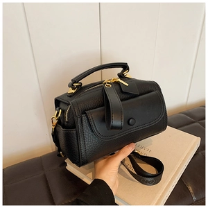 Dettaglio borsa Boston in pelle martellata nera con hardware dorato e tracolla larga