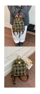 Close-up of green checkered tweed backpack with gold zipper and metal plate detail