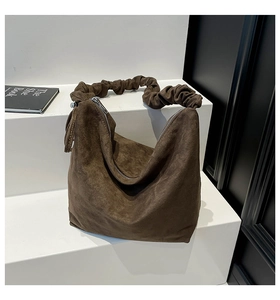 Detail showing the coffee brown suede tote bag with a unique ruched cloud-style handle