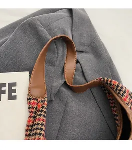 Detail of houndstooth shoulder bag with premium brown leather strap and reinforced stitching