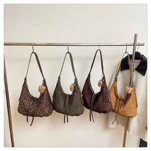 Close-up of suede hobo bags in leopard, olive, brown and yellow colors with bear charms
