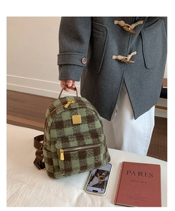 Detail of green plaid woolen mini backpack with gold zippers in a cozy autumn setting