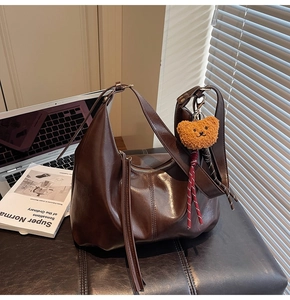 Detail view of smooth dark coffee leather hobo bag with cute plush bear charm