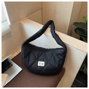 Détail du sac matelassé noir à motifs cœurs avec étiquette de marque et tissu premium
