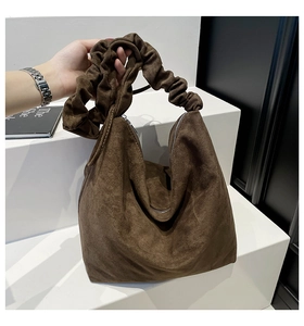 Detail of brown suede hobo bag featuring a pleated handle and premium metal zipper closure