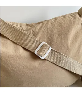Detail of adjustable khaki nylon shoulder strap with white resin buckle on a hobo bag
