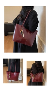 Detail of burgundy faux leather tote bag showing glossy texture and bead pendant