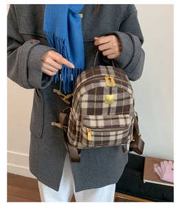 Detail of a mini plaid backpack with gold metal accents on a stylish wool texture