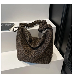 Detail of leopard print tote bag with scrunchie handle and secure zipper closure