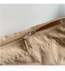 Close-up detail of smooth zipper and khaki nylon fabric texture on a large hobo bag