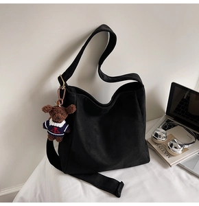 Détail d'un sac seau noir avec un charm ours en peluche dans un cadre de vie moderne