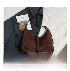 Detail of dark brown suede crescent bag with fringe decor and plush bear charm