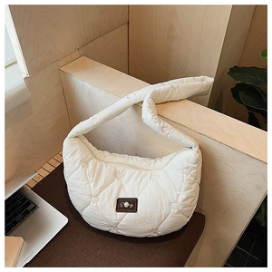 Détail du sac demi-lune blanc matelassé avec broderie cœur et écusson logo