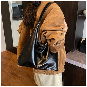 Close-up of black glossy oversized tote with contrast white stitching details