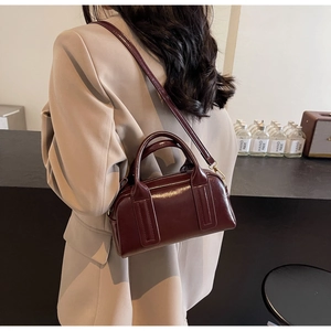Dettaglio borsa Boston in pelle verniciata bordeaux con finiture dorate e tracolla sottile