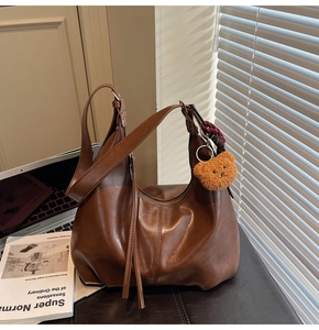 Detail of vintage brown leather hobo bag with tassel zippers and a cute teddy bear charm