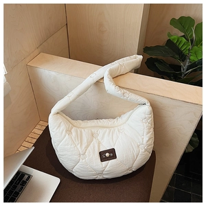 Détail d'un sac bandoulière blanc matelassé avec broderie coeur sur une surface en bois