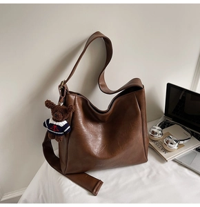 Détail d'un sac cabas marron foncé en similicuir avec un charmant petit ours en peluche