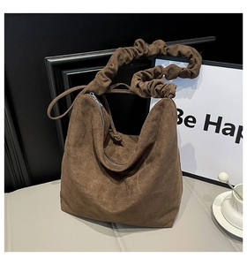 Close-up of brown suede tote bag with ruched handles and gold metal zipper detail