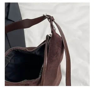 Detail view of the brown suede shoulder bag featuring a smooth metal zipper and leather strap