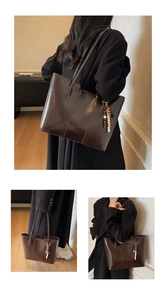 Detail of dark brown leather tote bag with stylish colorful wooden bead tassel pendant