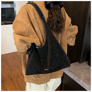 Detail shot of black suede hobo bag with contrast white stitching and minimalist logo