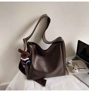 Gros plan d'un sac seau mat marron foncé avec un joli charm d'ours en peluche doux