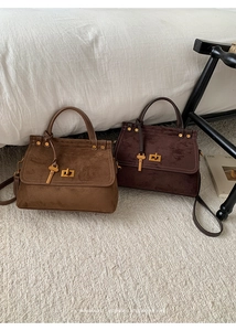 Detail of retro suede handbags in brown and coffee with elegant gold hardware and turn-lock