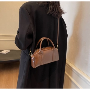 Borsa Boston vintage marrone con finiture dorate a tracolla in un contesto di vita reale