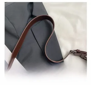 Detail of adjustable dark brown leather shoulder strap with neat stitching and metal buckle