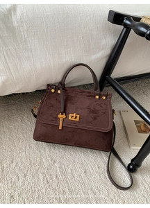Close-up of retro brown suede handbag with golden twist lock and metallic key charm