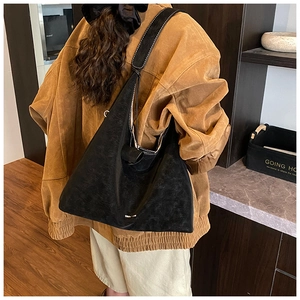 Detail showing the large black suede tote bag with drawstring and brand logo