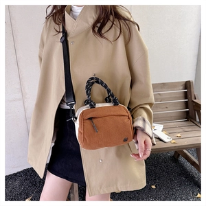 Detail of corduroy patchwork handbag featuring woven rope handles and front zipper pocket